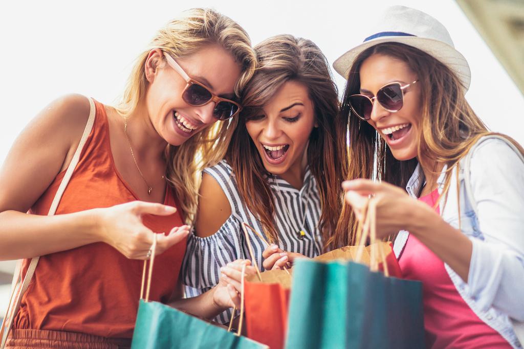 Three women looking inside their shopping bags.
